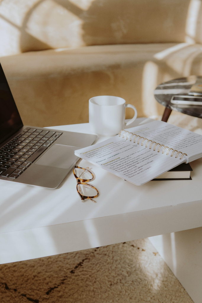 Desk with computer, notebook, mug, and glasses on it