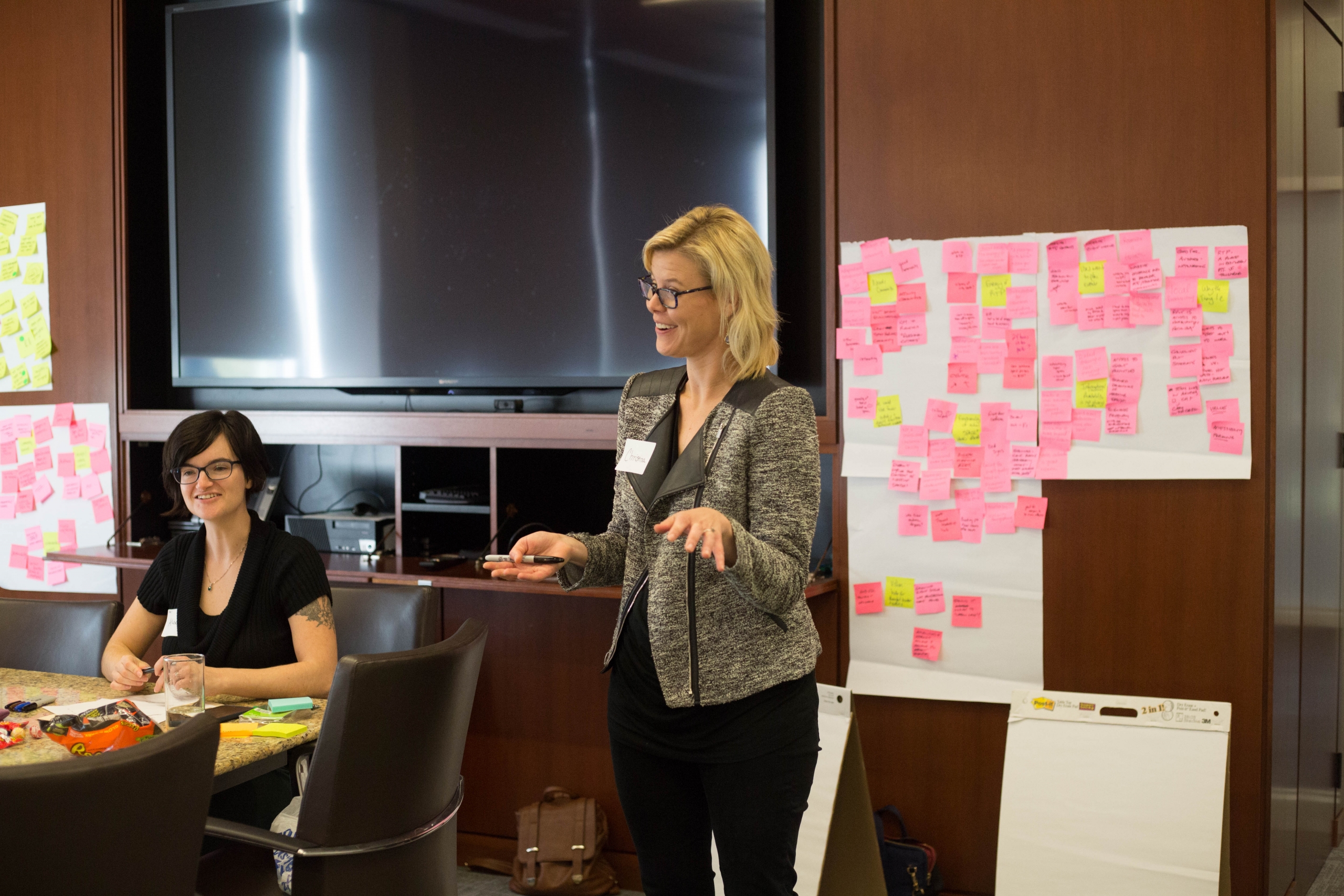 Christina standing at front of a room during a workshop with sticky notes behind her